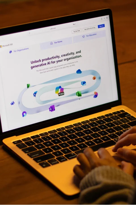Person using a laptop to explore a website showcasing Microsoft 365 and AI tools for productivity.